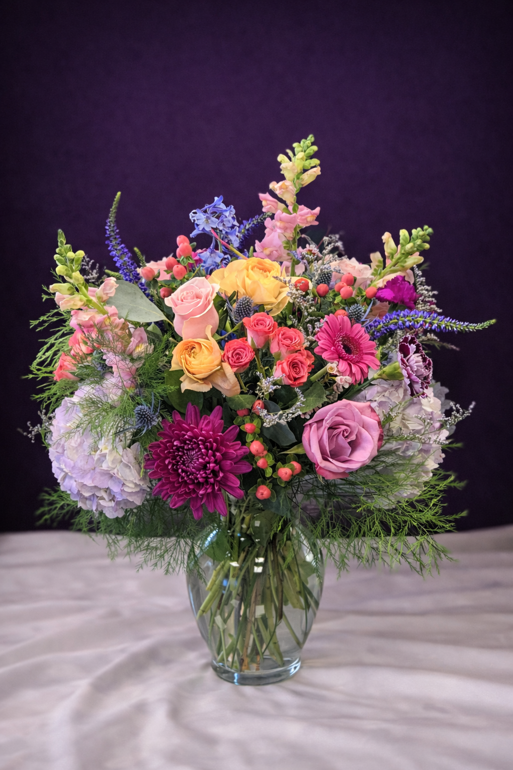 Bouquet of colorful flowers in a clear vase on a dark background