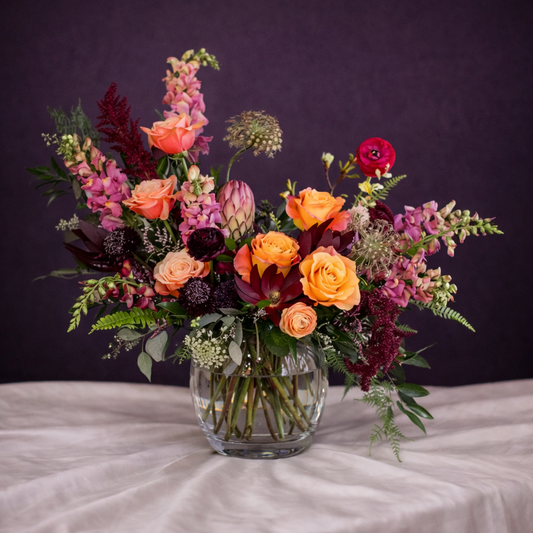 Colorful flower arrangement in a clear vase on a dark background